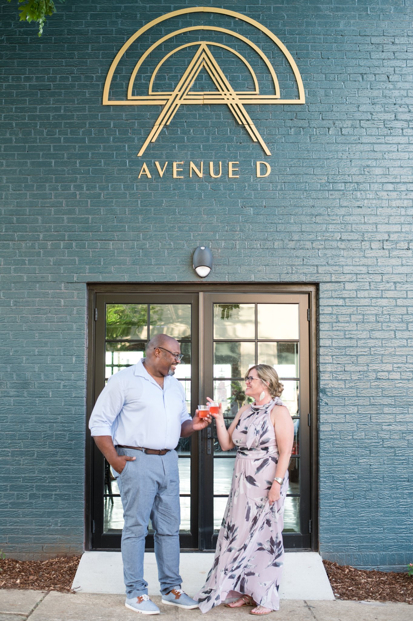 couple with bnb beverage management signature cocktails outside avenue d sign