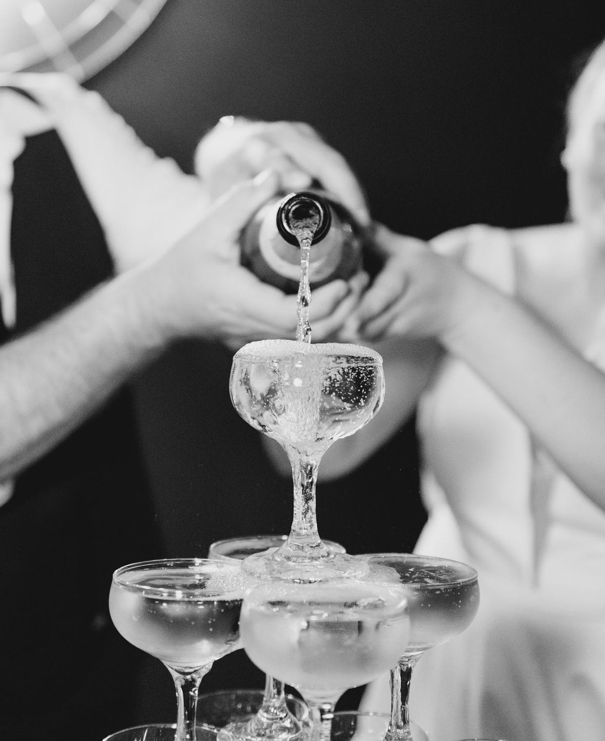 pouring champagne into self standing champagne tower at wedding at southerly warehouse black and white