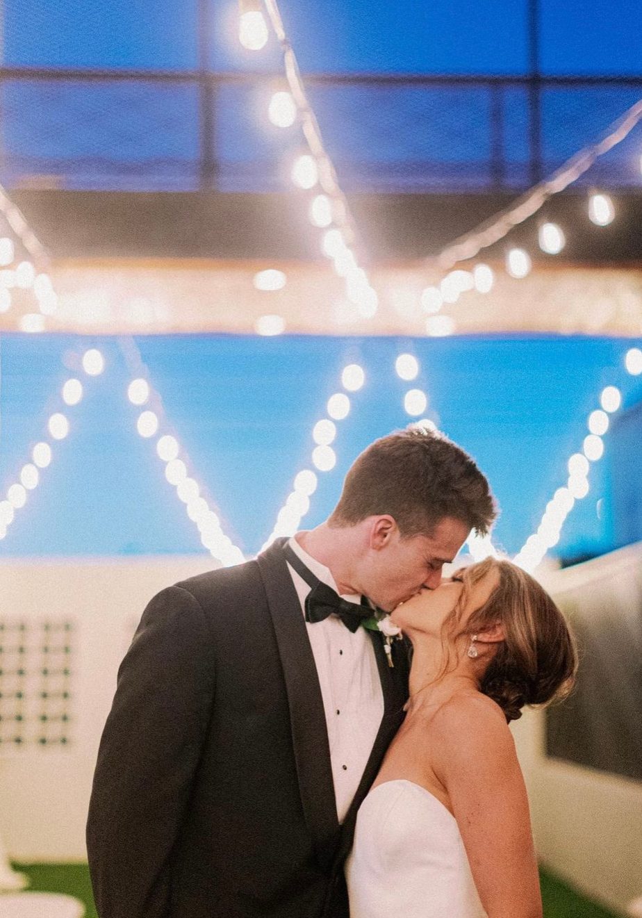 bride and groom kissing under fairy lights outside at southerly warehouse