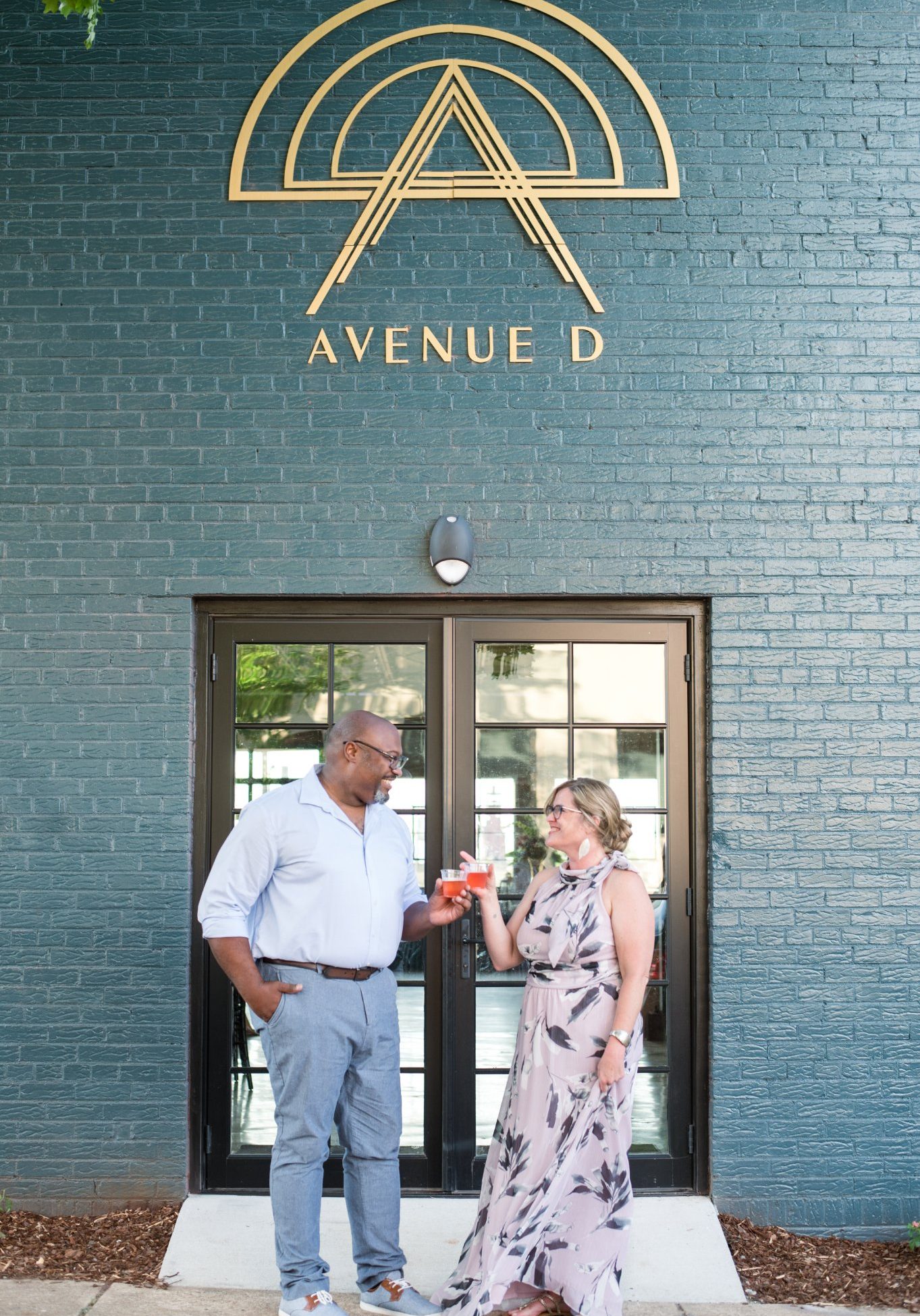 couple with bnb beverage management signature cocktails outside avenue d sign