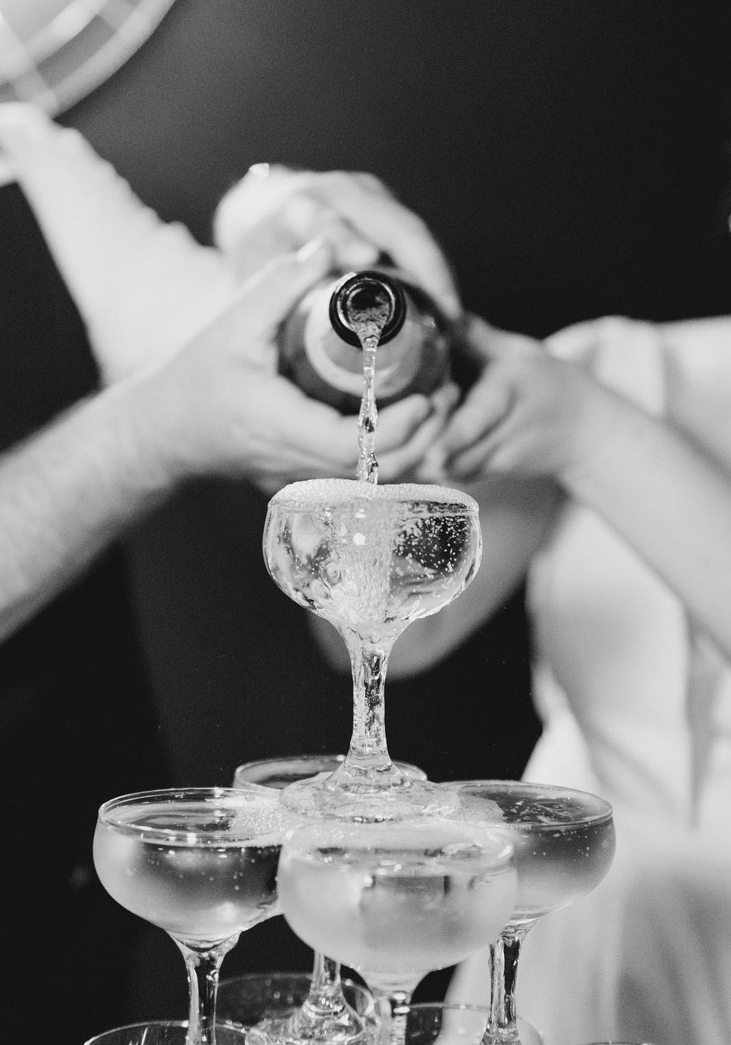 pouring champagne into self standing champagne tower at wedding black and white